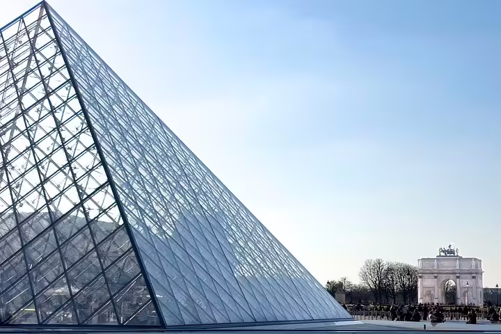 Louvre's glass pyramid with the Arc de Triomphe du Carrousel in the background, highlighting Parisian landmarks.