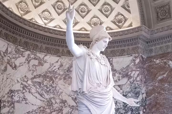 Explore the stunning marble statue of Athena in the Louvre Museum's ornate gallery on a guided tour with entrance ticket.