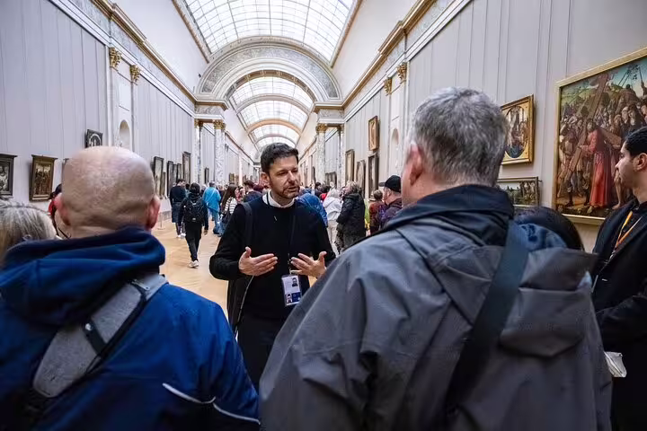 Tour guide leading a group through the bustling halls of the Louvre Museum during a guided tour experience.
