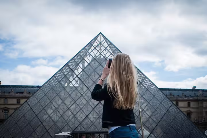 Visitor capturing the iconic Louvre Pyramid in Paris on a private city highlights tour for newcomers.