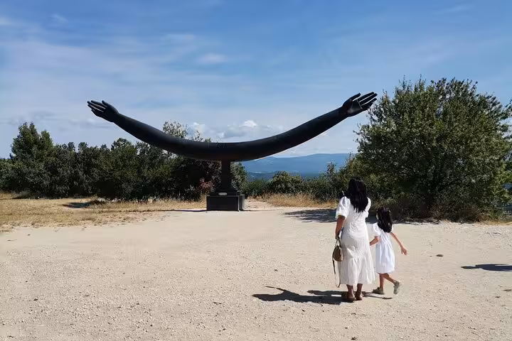 Visitors walking to a hilltop art sculpture viewpoint in Luberon, Provence, during a scenic wine tour day