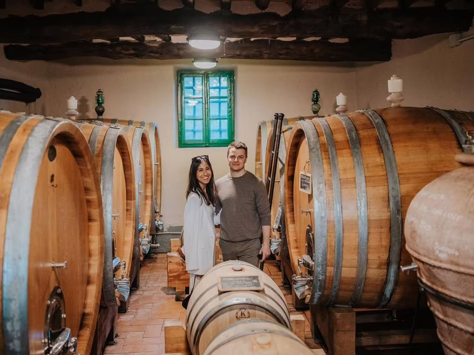 Visitors exploring a rustic wine cellar in Lucca, surrounded by large oak barrels during a winery tour and tasting.
