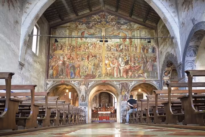 Historic church interior near Lugano with frescoed wall and wooden pews on guided tour from Como