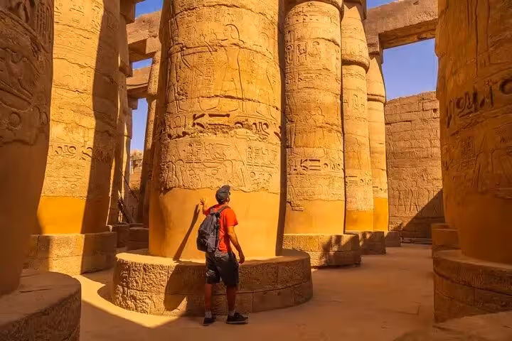 Traveler exploring Karnak Temple columns in Luxor on a private overnight tour from Hurghada, ancient hieroglyphs