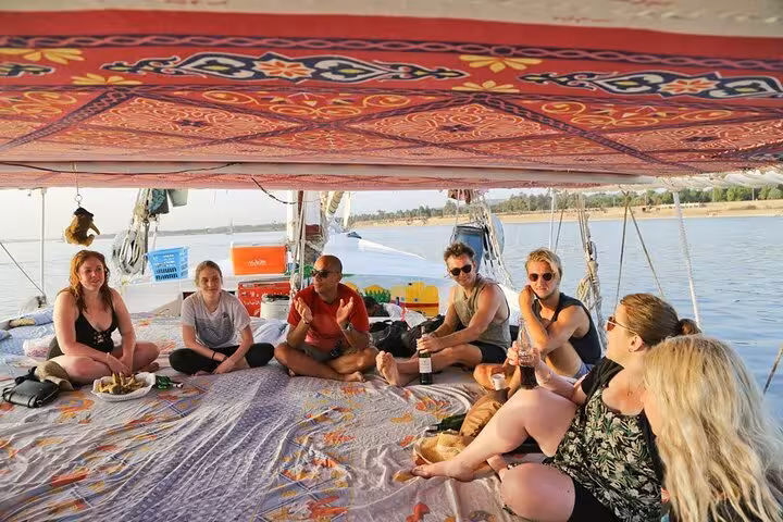 Travelers lounging on a traditional felucca boat on the Nile in Luxor, Egypt, private sailing tour stop