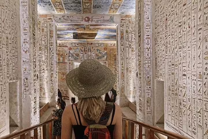 Traveler exploring hieroglyph-lined temple corridor in Luxor on a private Cairo to Luxor sleeper train trip