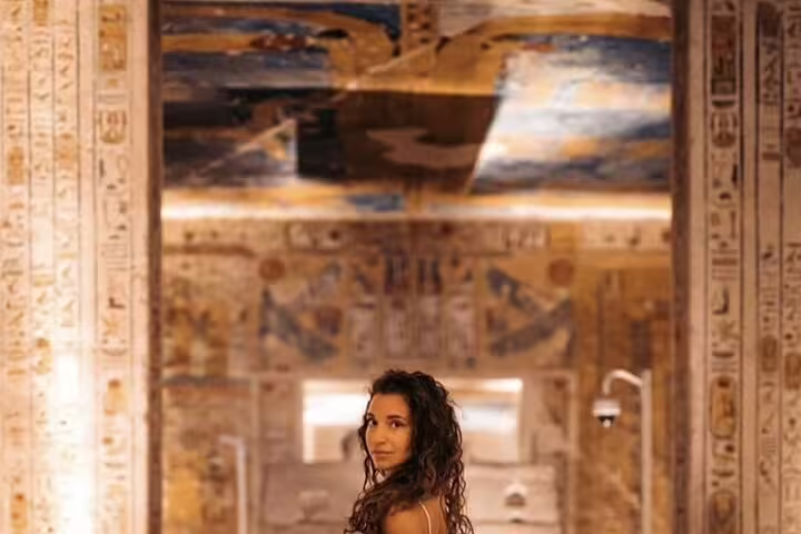 Traveler inside Luxor temple hall with colorful hieroglyphs, part of 3 nights 2 days Cairo to Luxor sleeper train tour