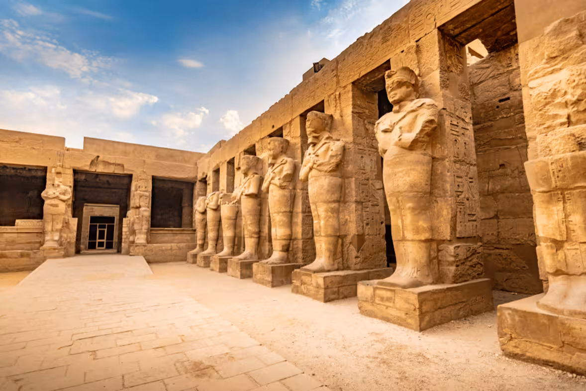 Courtyard of Luxor Temple with colossal pharaoh statues and hieroglyphs, must-see on Cairo to Abu Simbel Nile cruise