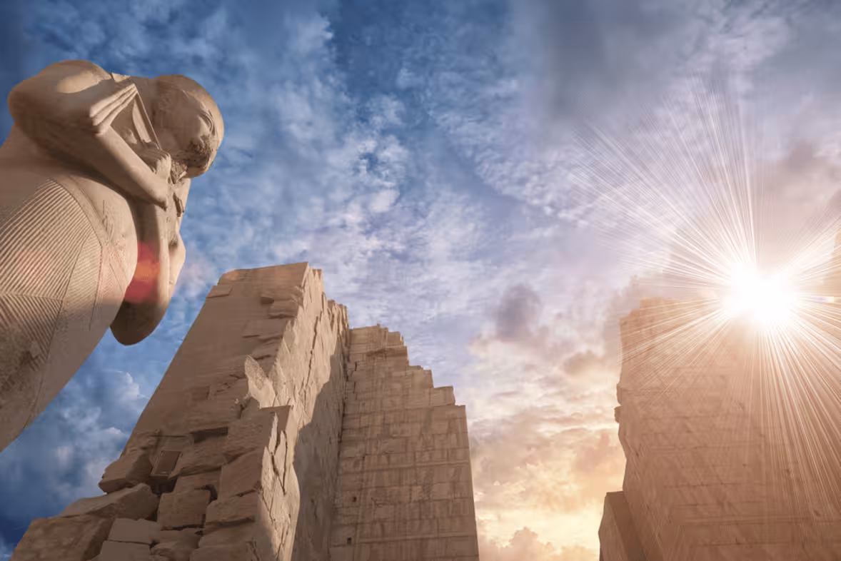 Sunburst over colossal statue and temple ruins in Luxor, iconic stop on budget Egypt tour to Abu Simbel