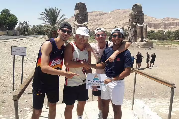 Travelers posing at Colossi of Memnon on a private full-day Luxor tour from Aswan by car with guide