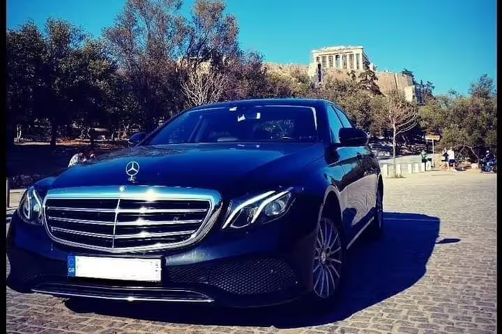Luxury black sedan for private transfer from Athens to Thessaloniki, parked near Athens landmarks