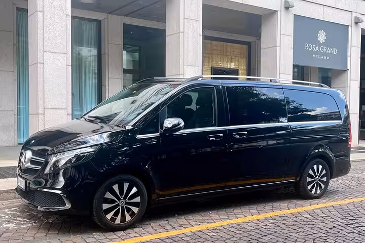 Luxury black van for private transfer from Milan to Interlaken, parked outside a Milanese hotel.