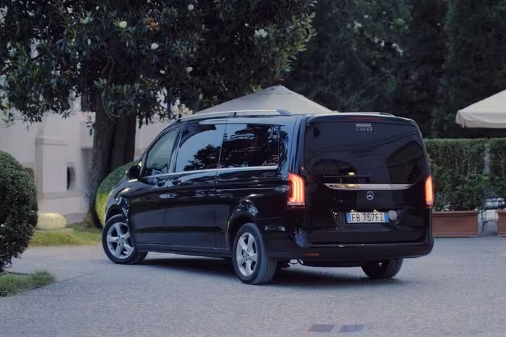 Luxury black van parked at Treviso Airport, ready for a comfortable transfer to Venice, surrounded by greenery.
