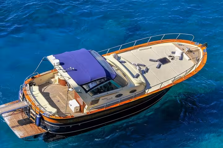 Luxurious boat with blue canopy cruising Sorrento Coast's clear waters, ideal for a Positano to Capri tour.