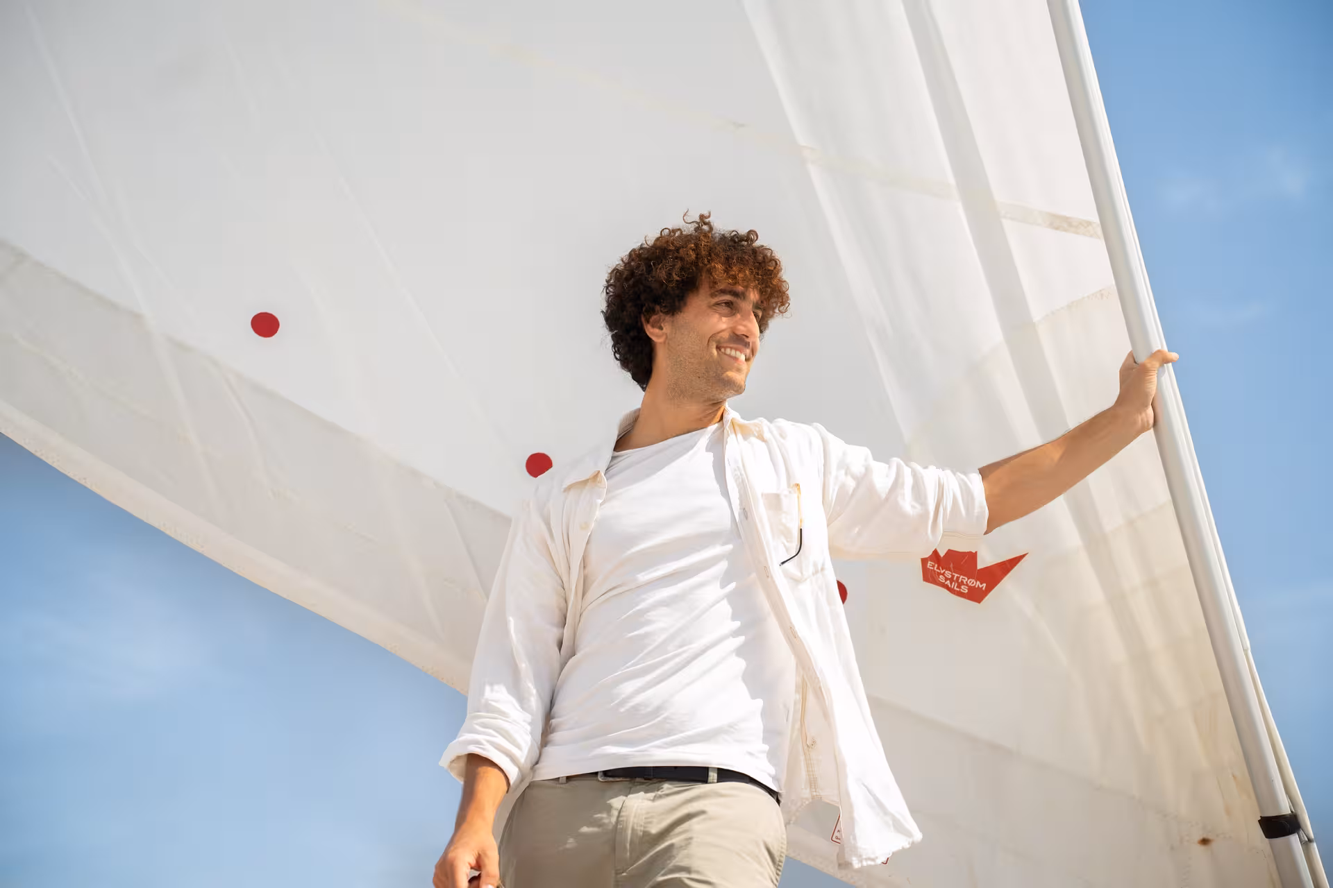 Smiling skipper by the sail on a private luxury catamaran Barcelona cruise, Bali 4.2 experience