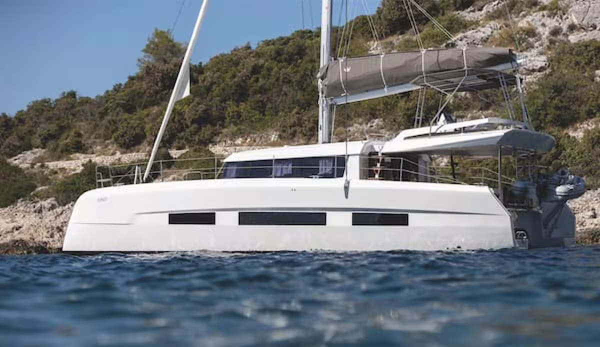 Modern luxury catamaran anchored near the rocky coastline by Procida, offering a relaxing VIP full day sailing experience