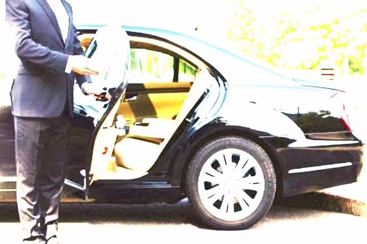 Chauffeur opening door of luxury black sedan for private transfer service between Sorrento and Rome city hotels