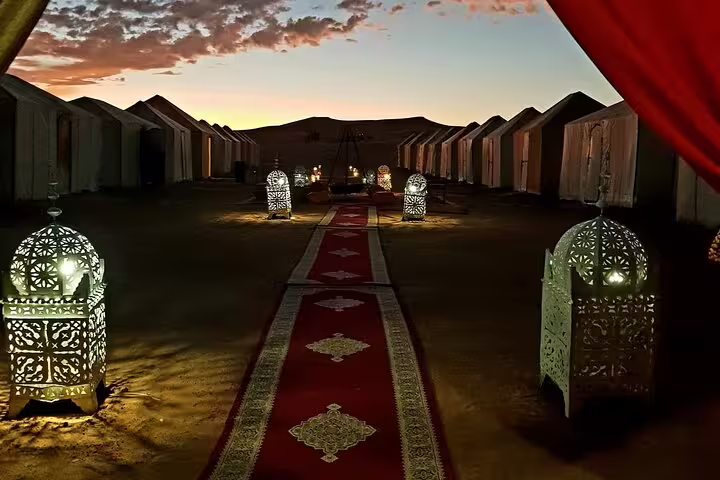 Luxury Sahara desert camp at sunset with lantern-lit walkway, Morocco 10-day tour from Casablanca