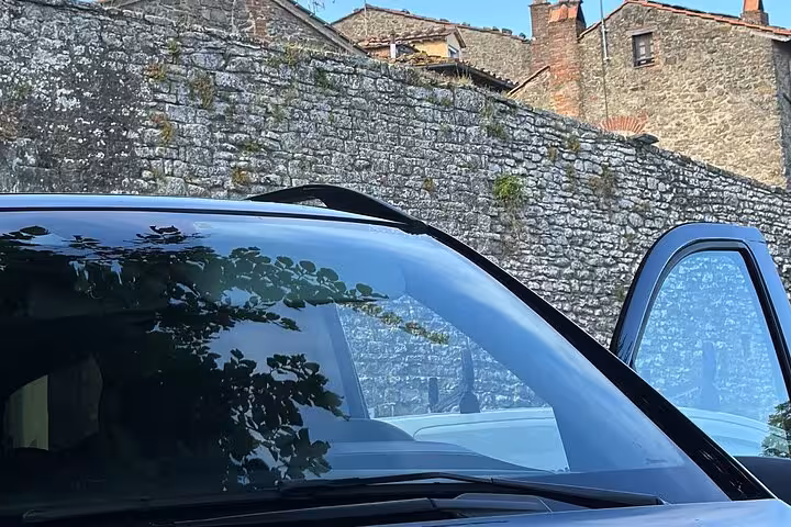 Luxury van parked against historic stone wall, ready for private day tour from Rome to Assisi.