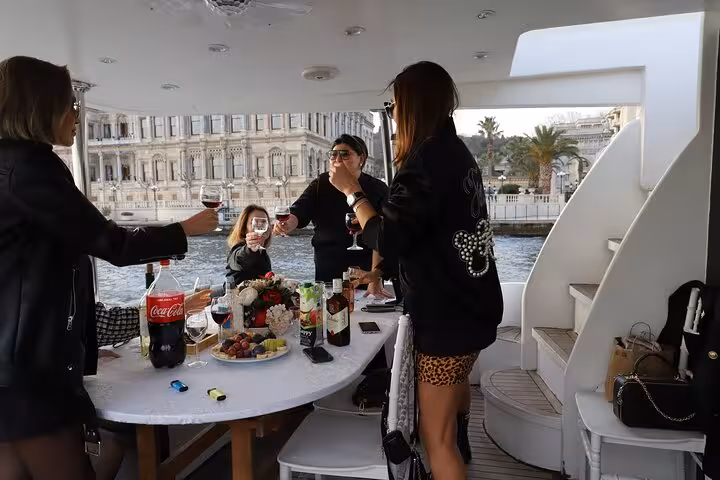 Guests toasting with wine on luxury yacht for private Bosphorus cruise in Istanbul, passing waterfront palaces