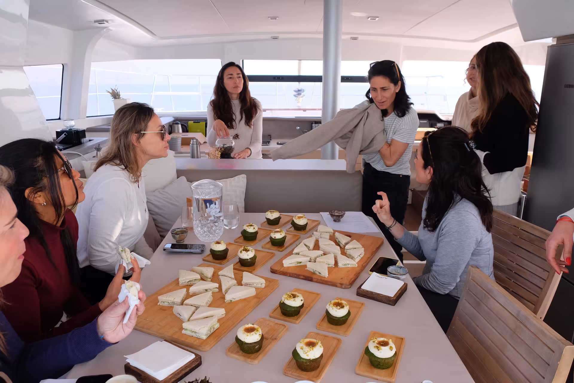 Guests enjoy a guided tea ceremony with traditional sweets and sandwiches aboard a luxury yacht lounge