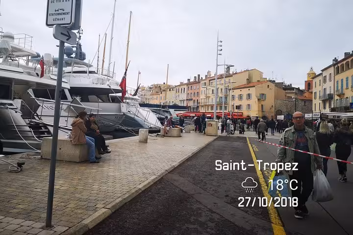 Luxury yachts moored at Saint-Tropez harbor with waterfront walkway, day trip tour from Bormes-les-Mimosas