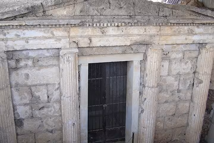 Stone Macedonian tomb entrance with columns and sealed door, visited on Alexander the Great private tour from Athens