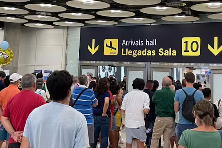 Crowd at Madrid Barajas Airport arrivals hall sign, meeting point for private transfer from airport to Madrid