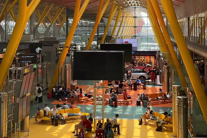 Busy Madrid Barajas Airport departures hall with seating, perfect for pre-booked private transfer to Madrid hotel