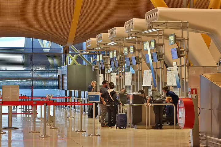 Madrid Barajas Airport check-in counters with travelers, ideal for private transfer to central Madrid hotel