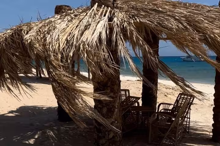 Palm-leaf beach hut with chairs on Magawish Island, Hurghada, relaxing stop on private speedboat tour
