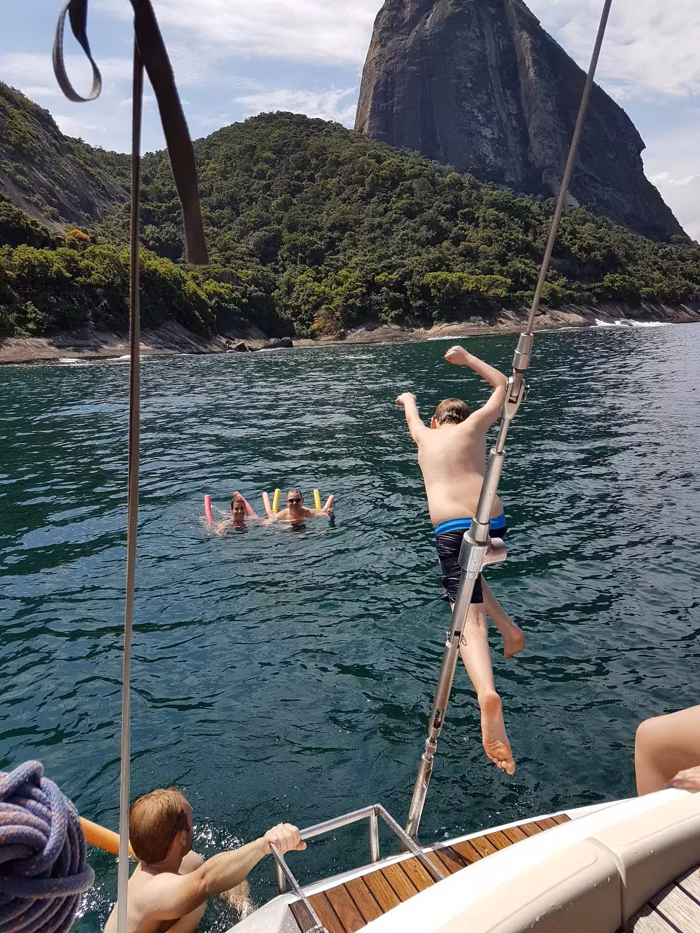 Excited passengers dive into crystal-clear waters from MAKANI MAIKAI yacht, exploring vibrant marine life.