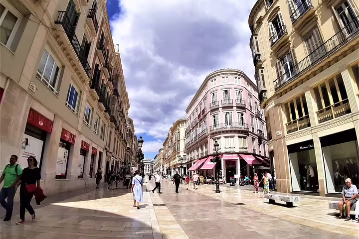 Group walking tour along Malaga’s Calle Larios, historic Old Town street with shops and elegant facades