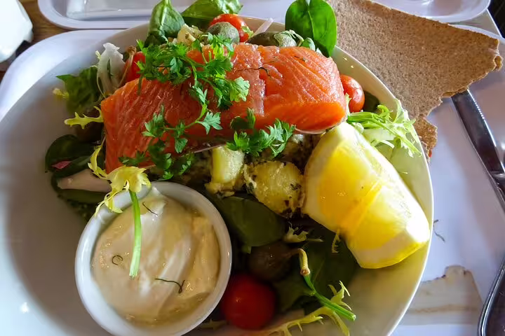 Fresh Nordic salad with smoked salmon, greens, lemon, and dressing, served on a Malmö day trip from Copenhagen by train.