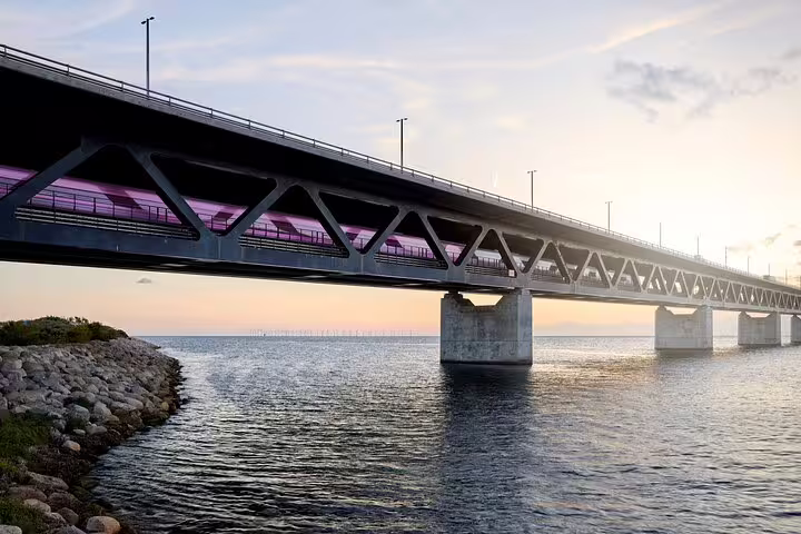 Train crosses the scenic Øresund Bridge at sunset during a Malmö private full-day trip from Copenhagen by train.