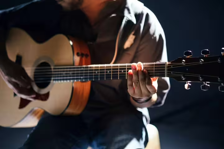 Close-up of a musician strumming an acoustic guitar during a Maltese Folklore Night Tour performance.
