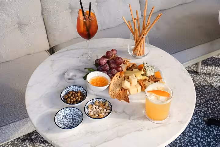 Marble table with Italian aperitif spread of cheeses, grapes, breadsticks, and cocktails on the MaMa Florence tour.