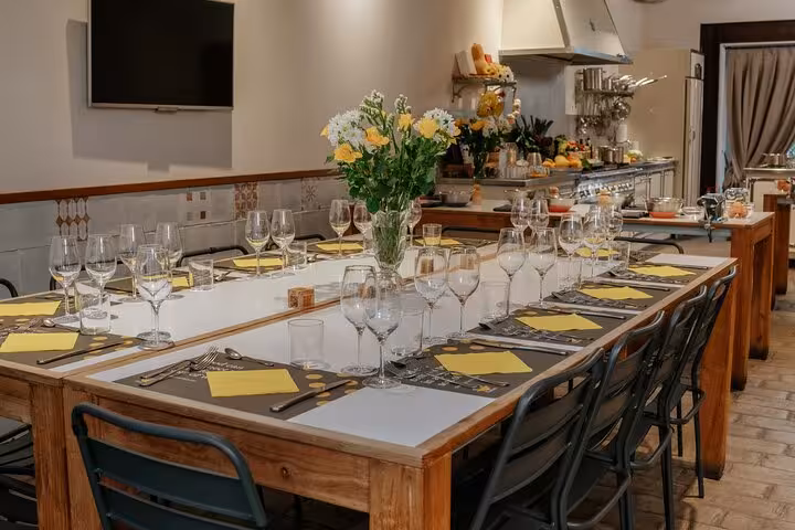 Elegant dining setup for MaMa Florence market tour and pasta cooking class, featuring a long table and wine glasses.