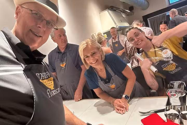 Group of participants enjoying MaMa Florence's pasta cooking class, smiling and posing at the kitchen table.