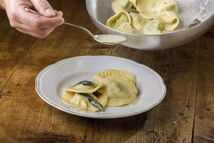 Freshly made ravioli being expertly plated with sauce during the MaMa Florence pasta cooking class.