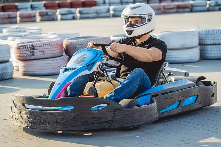 Man driving blue go-kart past tire barriers at Ghibli Raceway, Sharm El-Sheikh karting day trip