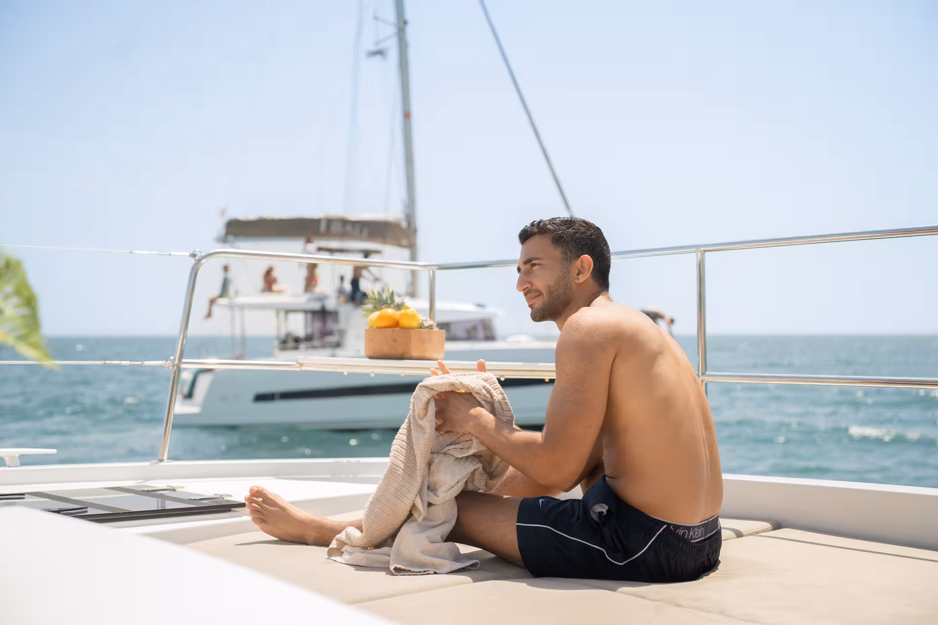 Man lounging on Bali 4.2 catamaran with fruit platter on a 2-hour private luxury cruise in Barcelona