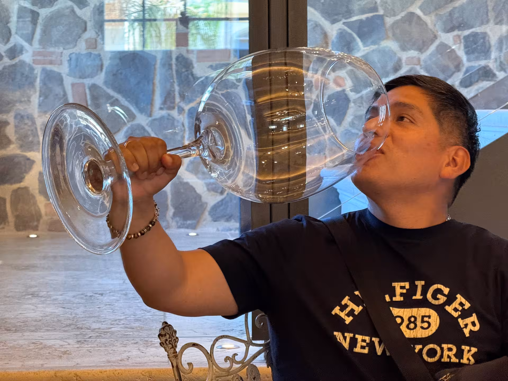 Man humorously sipping from an oversized wine glass inside a winery during a private Tuscany wine tour.
