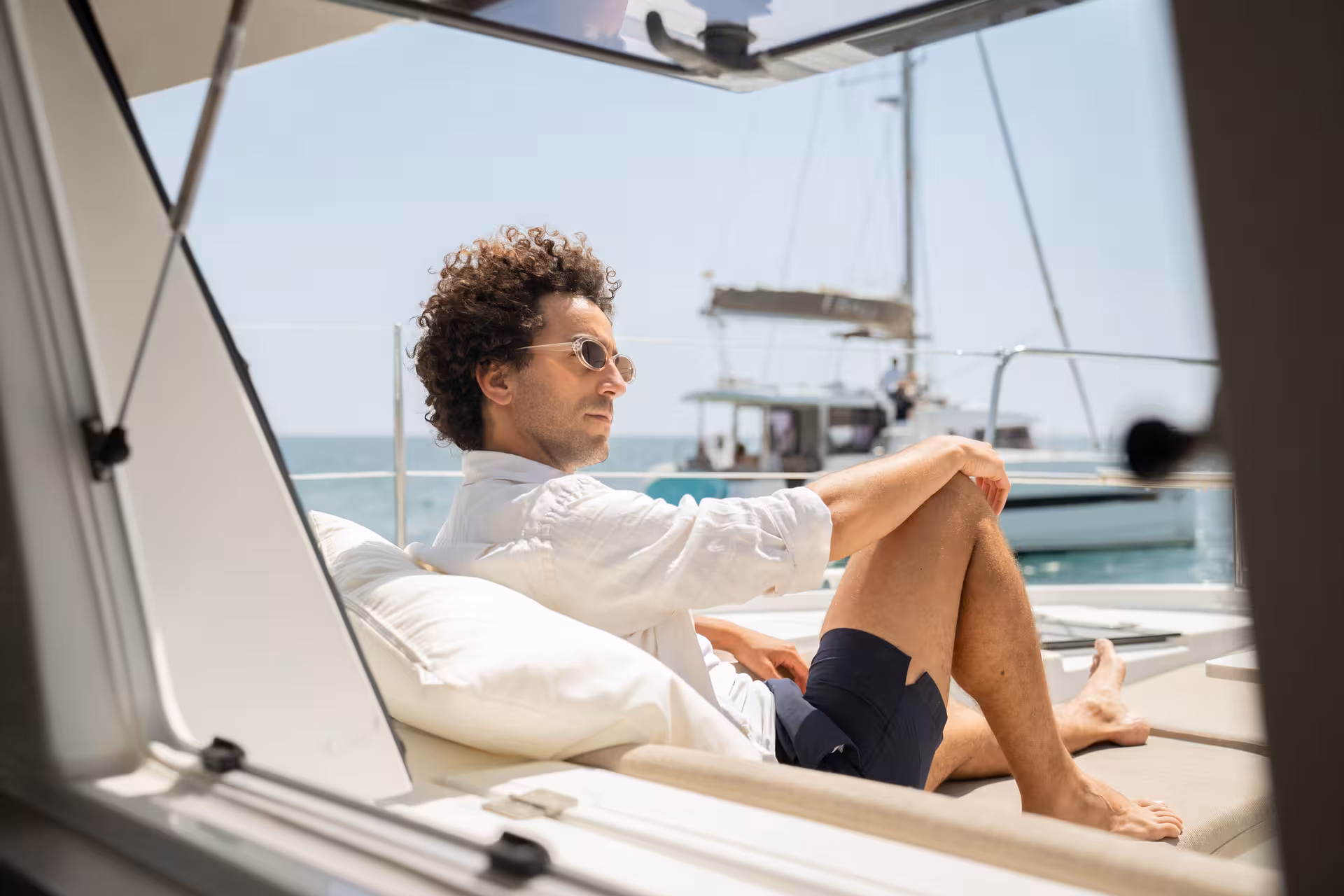 Man relaxing on deck cushions aboard Bali 4.2, private 4-hour luxury catamaran cruise from Barcelona