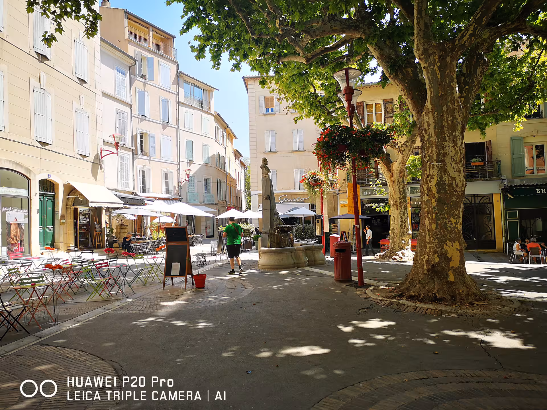 Shaded village square in Manosque Provence with cafes and fountain, visited on Marseille private shore excursion