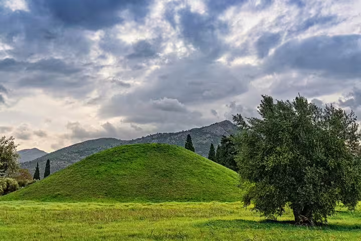 Grassy burial mound at Marathon battlefield with mountains, key site on Athens to Marathon half-day tour