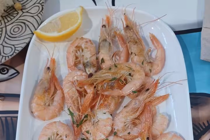 Plate of grilled prawns garnished with herbs and lemon, showcasing Marbella's authentic seafood flavors.