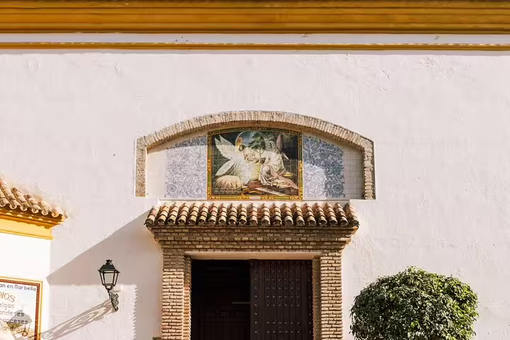 Charming entrance of a historic building in Marbella Old Town features a detailed mural above the doorway.