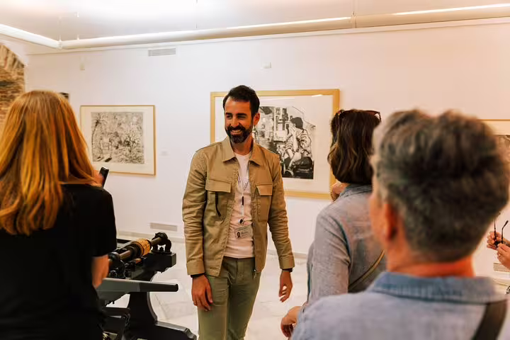 Visitors engage with a guide in an art gallery, exploring cultural highlights on a Marbella Old Town walking tour.
