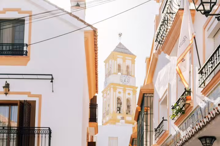 Scenic view of Marbella Old Town's picturesque streets with a historic church tower in the background.